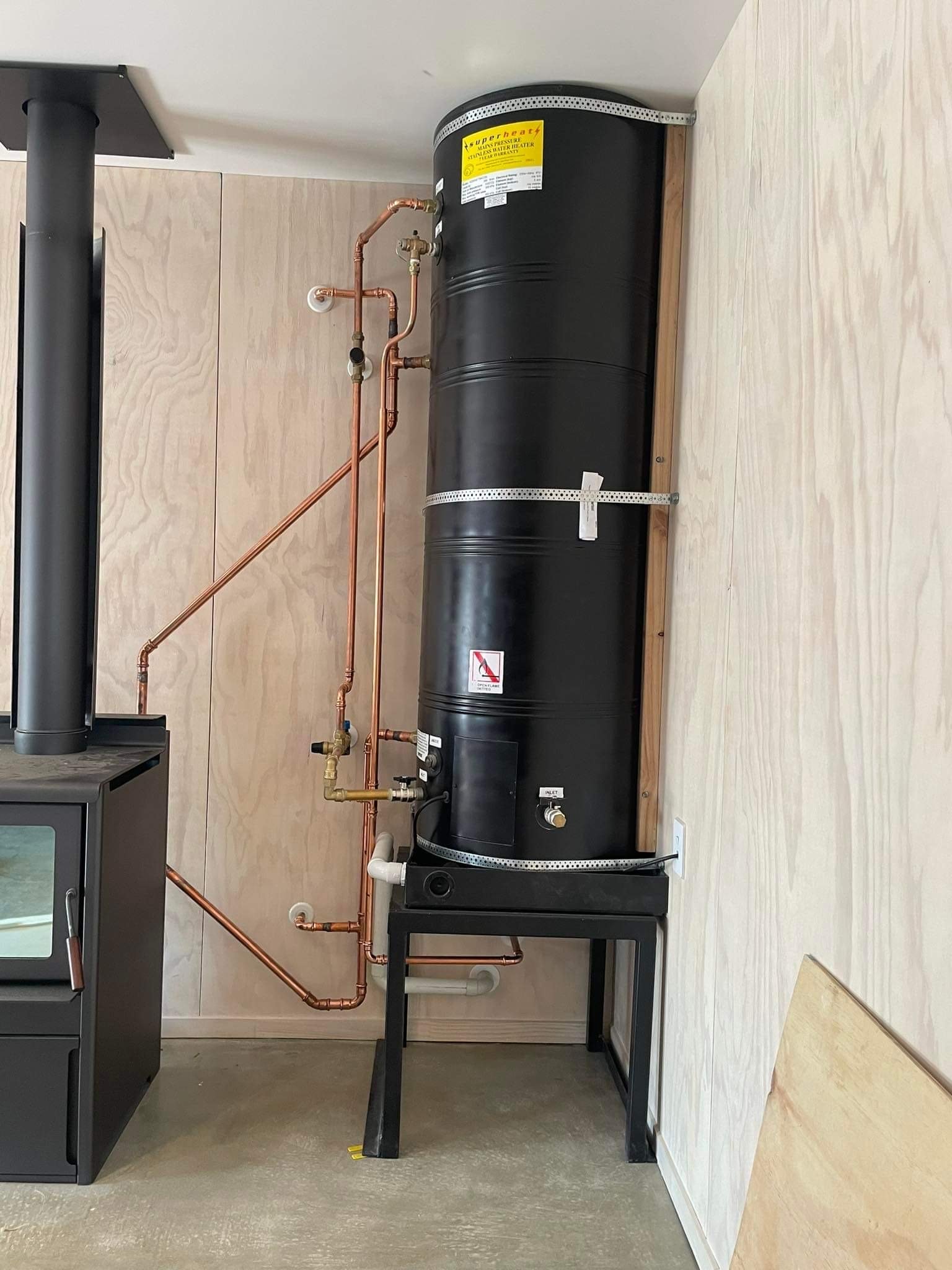 Black Superheats indoor cylinder beside a wood burner with fresh copper pipework, Christchurch
