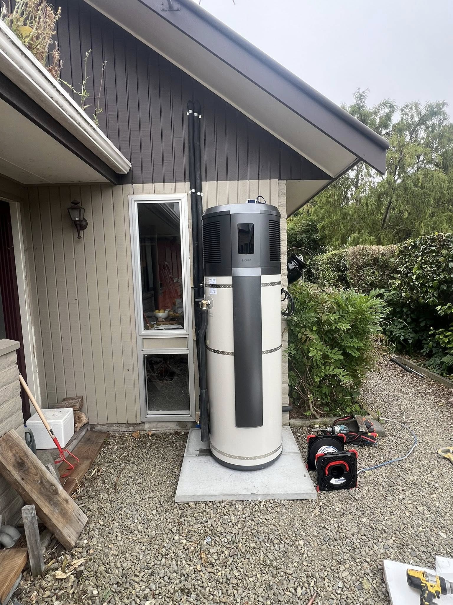 Carrier heat pump hot water unit installed outdoors next to a Christchurch home, mid-job
