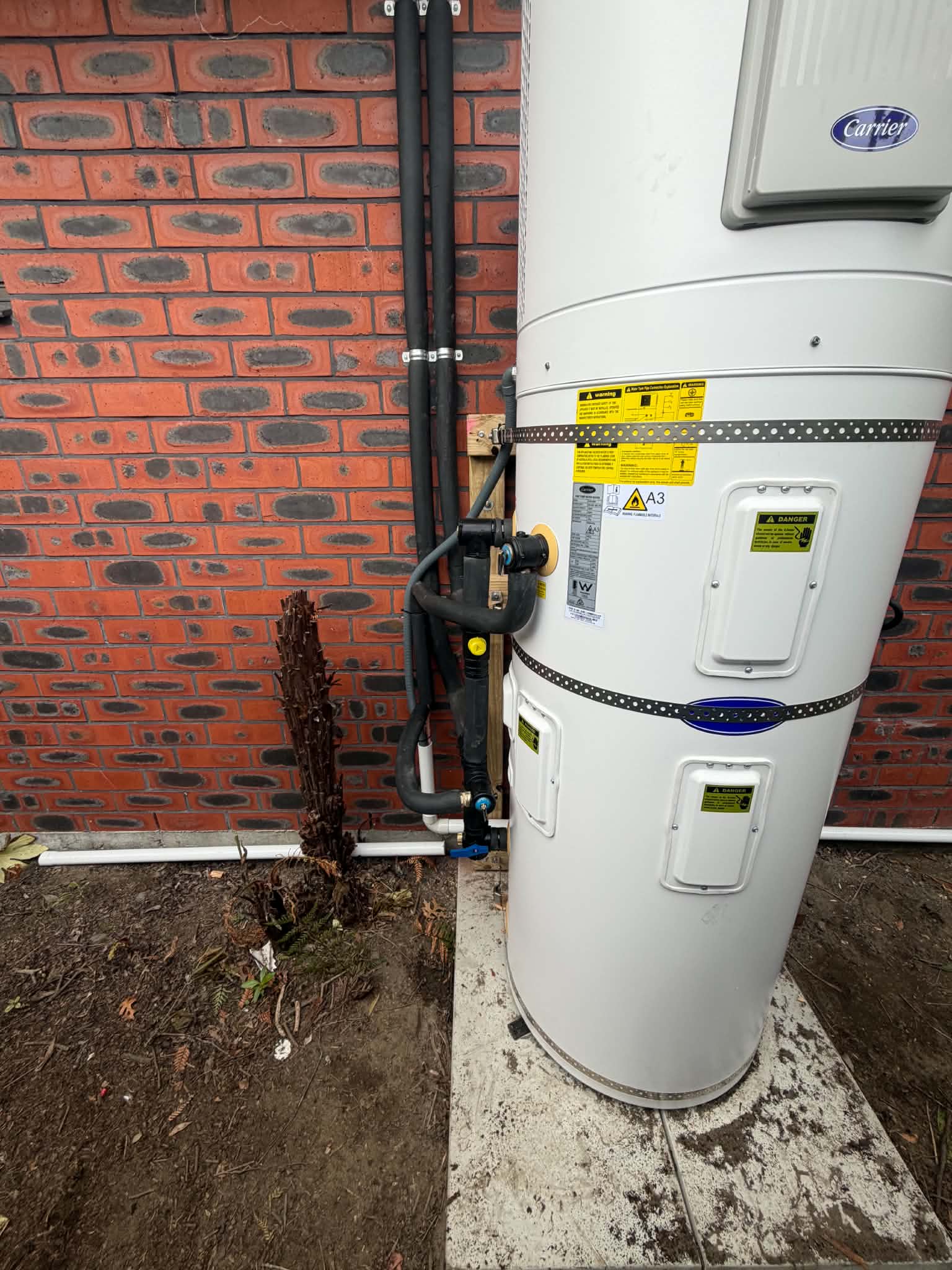 Carrier mains pressure cylinder installed outside against a red brick wall